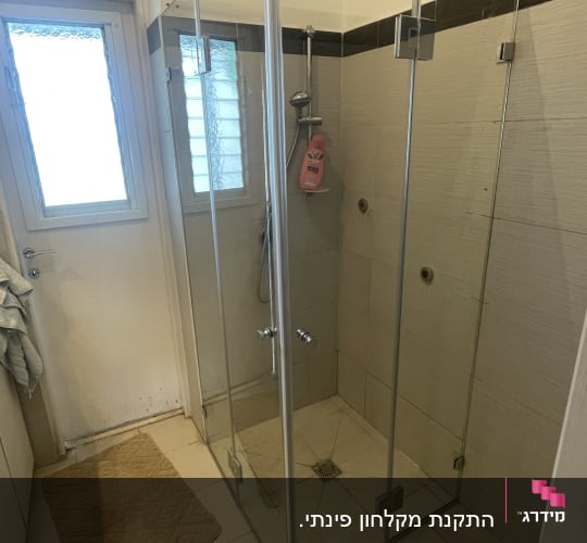 מקלחון זכוכית עם בקבוק סבון תלוי על מוט